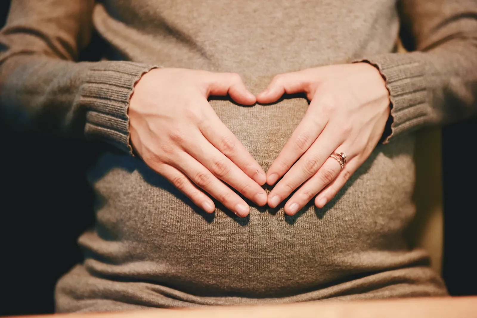 Schwangere formt mit ihren Händen ein Herz auf dem Babybauch